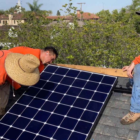 Technicians installing a solar water heater system on a residential roof.